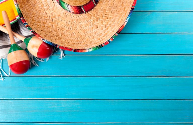 Mexican sombrero and maracas with traditional serape blanket laid on an old blue painted pine wood floor